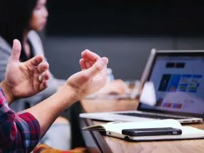 people in a meeting with a laptop and cellphone