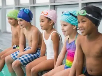 children sitting on the edge of a swimming pool