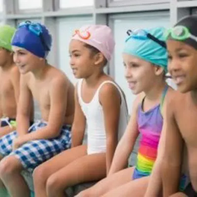 children sitting on the edge of a swimming pool