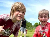 Two young children covered in foam, grinning, with the older child giving a thumbs up.