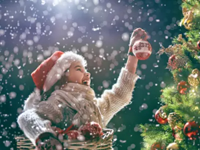 little girl placing ornaments on tree