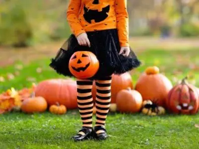 Little girl in halloween costume with pumpkins behind